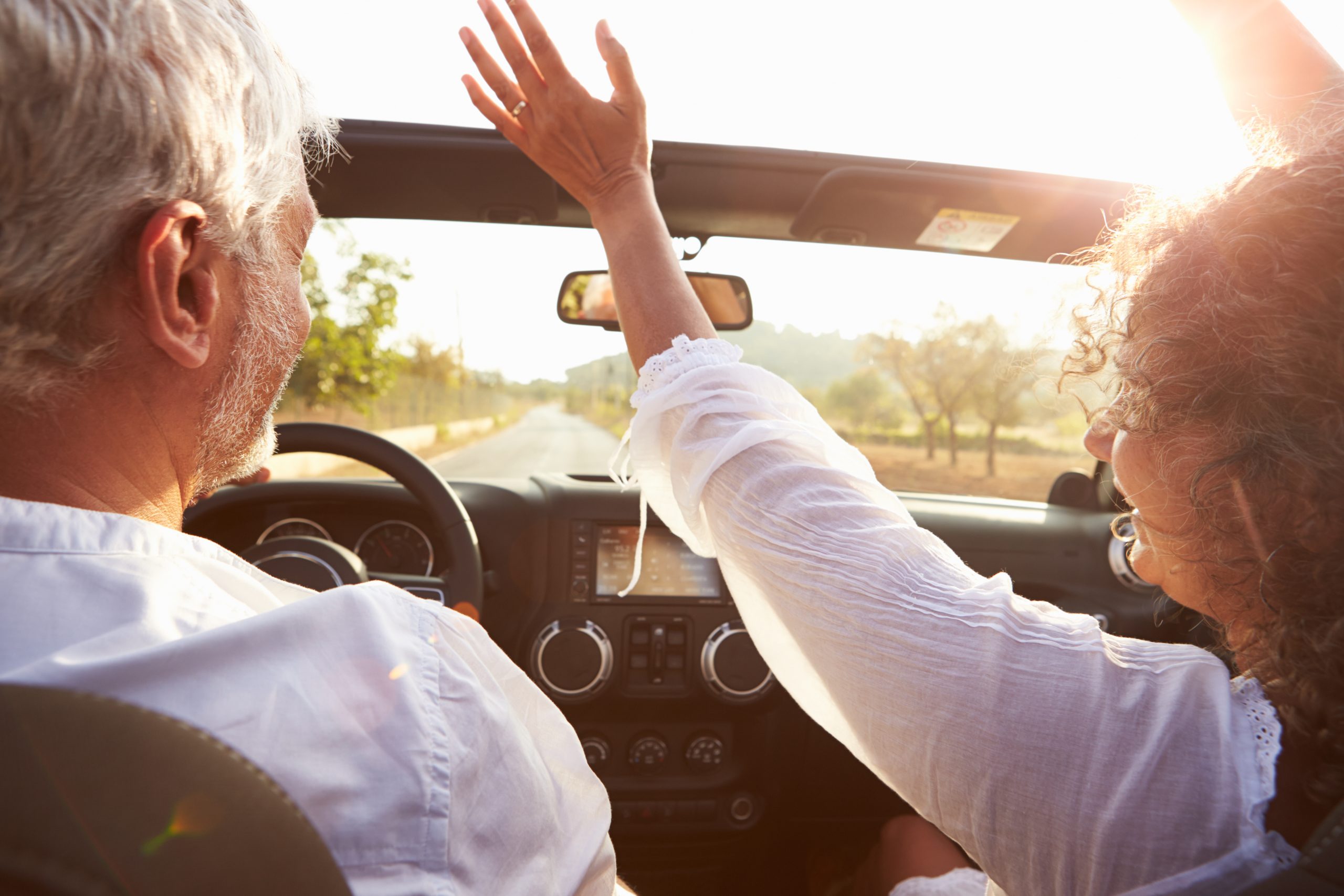Man driving with arm out of car window at sunset