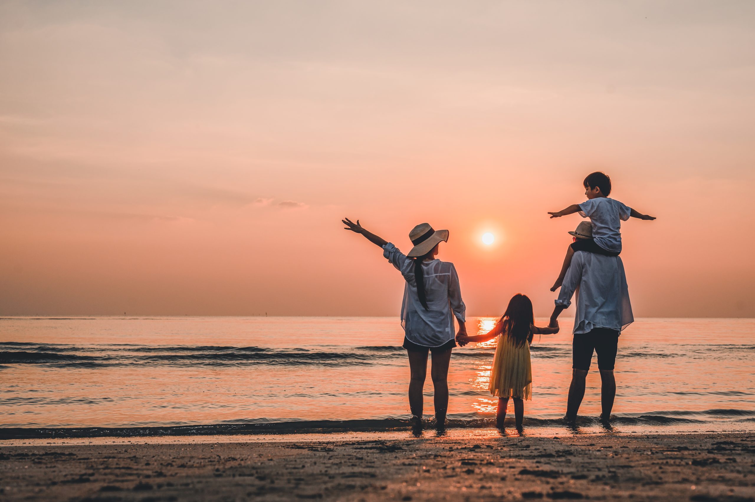 Young girl pointing at sunset while standing on the beach
